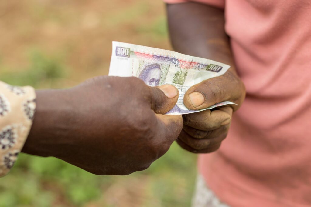 pexels-photo-15556066-15556066 kenyan travel guide, Captured moment of two individuals exchanging kenyan currency outdoors in Kenya.
